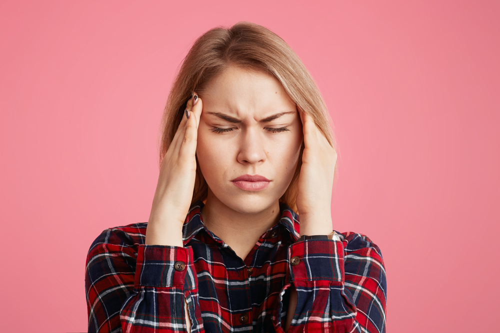Depressed stressful female has headache, keeps hands on temples, closes eyes as feel terrible pain, being overworked and fatigue, tries to concentrate and gather with thoughts. Tiredness concept